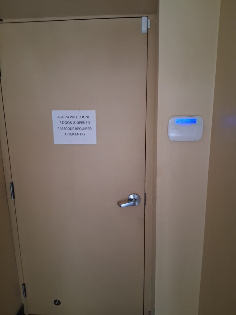 Access-controlled commercial door in Ottawa with magnetic contact, request-to-exit keypad and alarmed-entry signage
